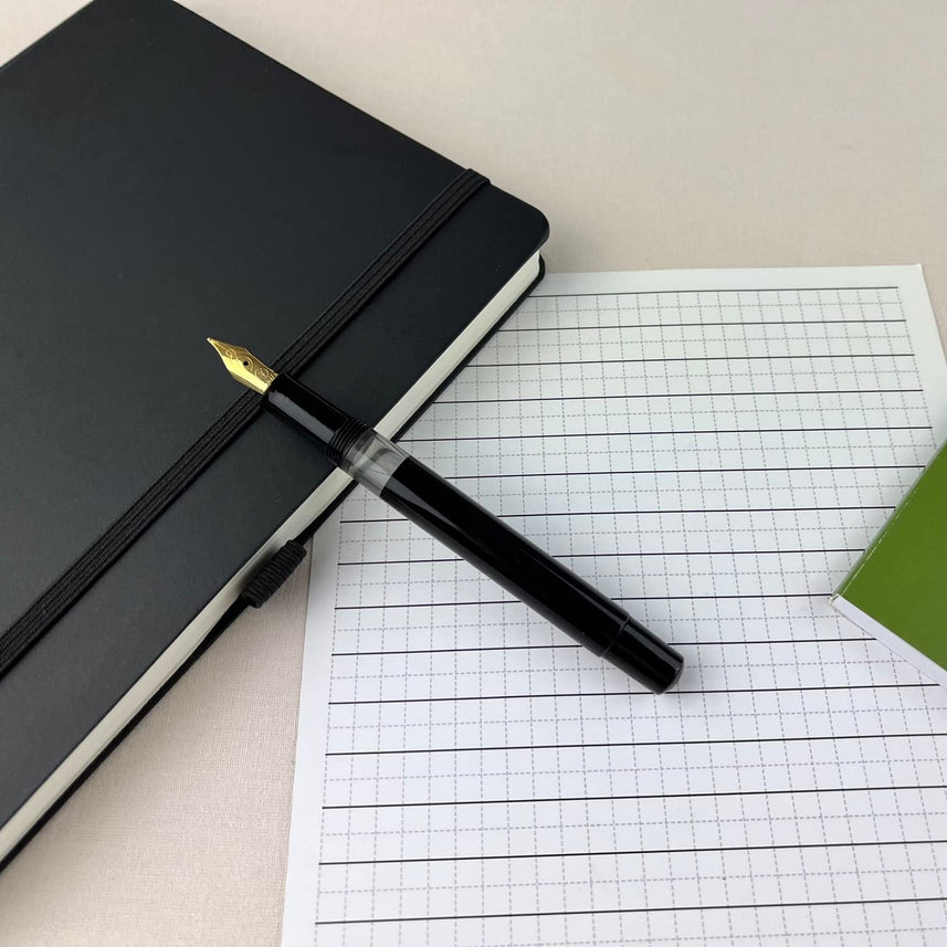Scrikss 419 Medium Nib Fountain Pen in Black GT on a squared sheet and diary